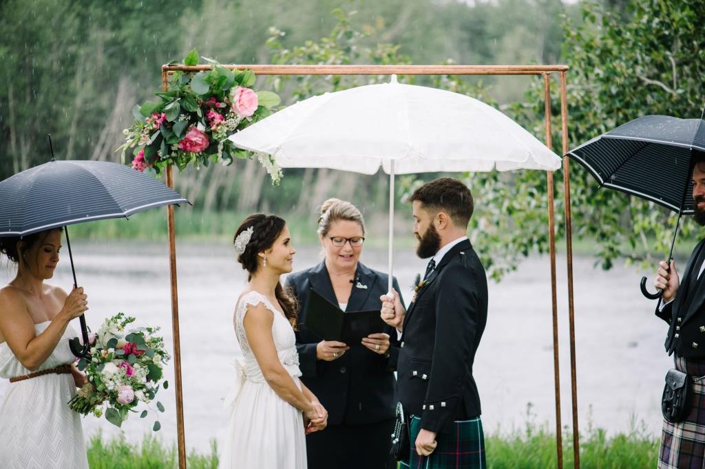Wedding ceremony under umbrellas outdoors.
